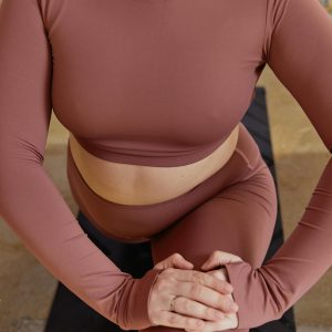 A close-up of a woman in activewear performing a yoga stretch indoors.
